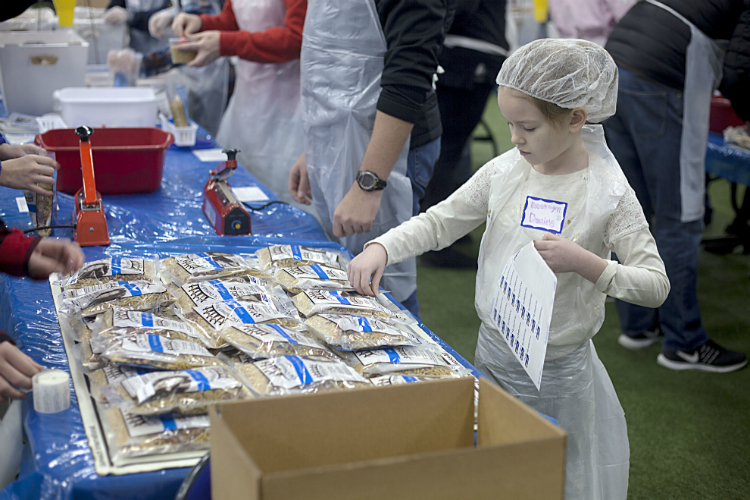 Brooklyn Daniels, 7, works along with her mother Tammi Daniels of Grand Blanc West Middle School to tag meal bags.