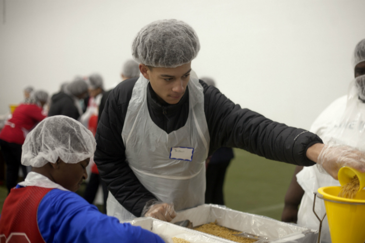 Jody Jackson, 11, and Jaylen Johnson, 14, work together to fill macaroni into bags. 