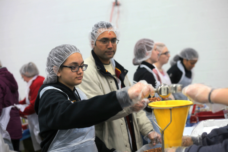 Susmit Patel and his daughter, Salony, 13, pour grains and fill bags of dry goods. They were among a large group of volunteers from Grand Blanc schools. 