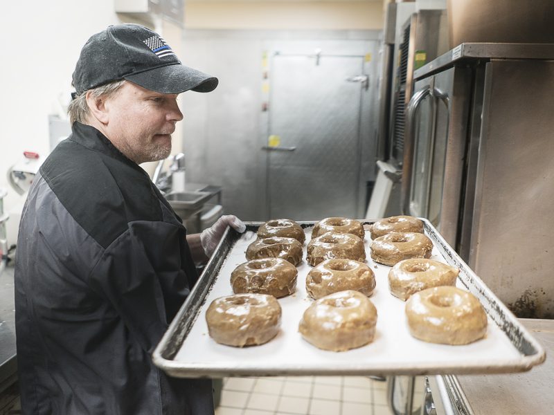 Bruce Sowles, 53, of Flint, carries a tray of fresh donuts to prepare them for delivery at Blueline Donuts, inside of Carriage Town Ministries.