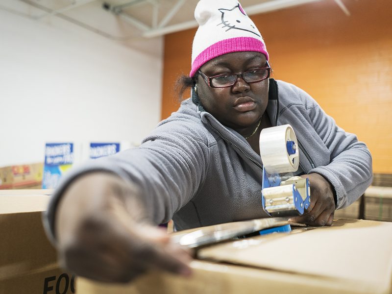 Jacquece Dent, 38, of Flint, tapes a large box full of food for a family holiday meal before it is loaded up and shipped out from the Food Bank of Eastern Michigan.