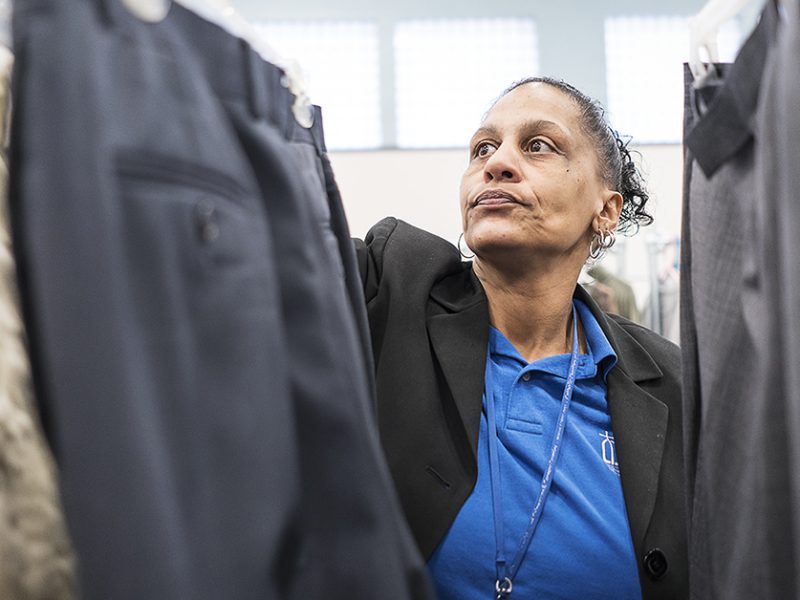 Community Closet Coordinator at the Catholic Charities Center for Hope Redonna Riggs, 47, of Flint, organizes donated clothing hanging from a clothing rack.