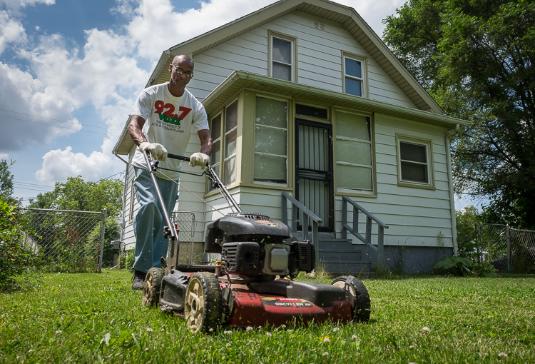 Quintin Evans uses a mower borrowed from the Community Tool Shed to mow elderly neighbors' lawns.