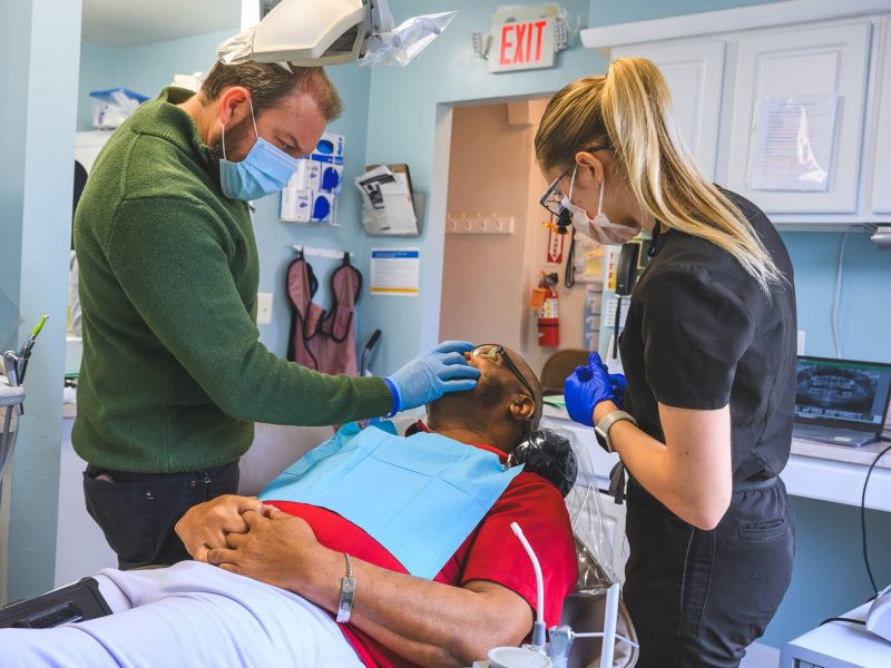 Dr. Ken Marriott, patient Thomas Jones, and dental hygienist Sarah Cawthon at the VINA Community Dental Clinic in Brighton.