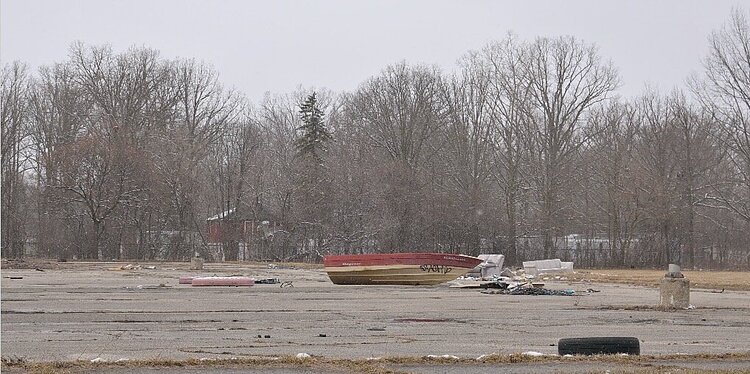 Sprawls of trash, including tires, mattresses, and an abandoned boat lay in the parking lot of Northern High School in Flint, Michigan on March 13, 2023. (Tia Scott | Flintside)
