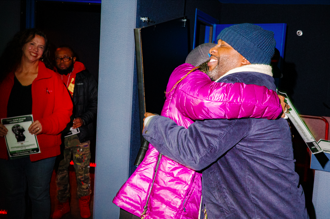 Jon Connor embraces a proud friend at the listening party for his newest album "III" at Longway Planetarium in Flint on Wednesday, Jan. 24, 2024. (Michael Indriolo | Flint Beat)