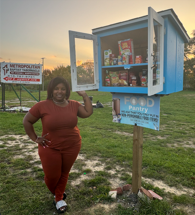 Chia Morgan stands next to one of four Well of Hope's free-standing food pantries in Flint.