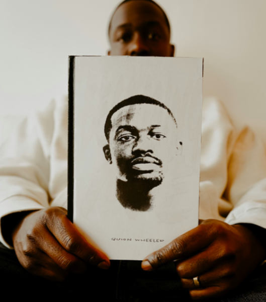 Flint native Quion Wheeler holds a copy of his debut book 'Becoming Me.'
