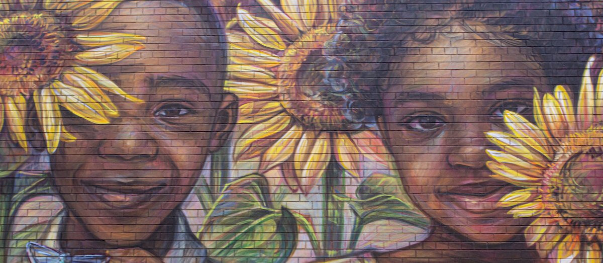 The Ennis Center for Children's wall displays a vibrant mural of children and sunflowers, created by artist Emily Ding.