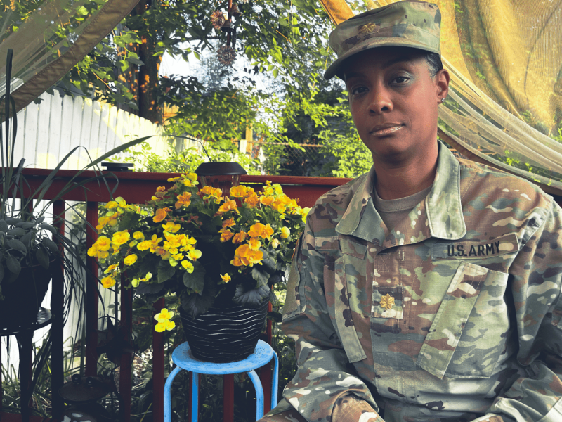 Major Michelle Hill sits outside in uniform discussing her goal of becoming Colonel with Flintside community correspondent Eartha Logan.