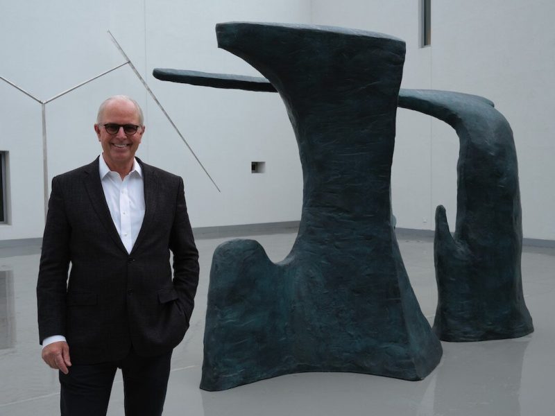 Flint Institute of Arts executive director John Henry standing in front of 'Paradise' in the FIA's Hurand Sculpture Courtyard.