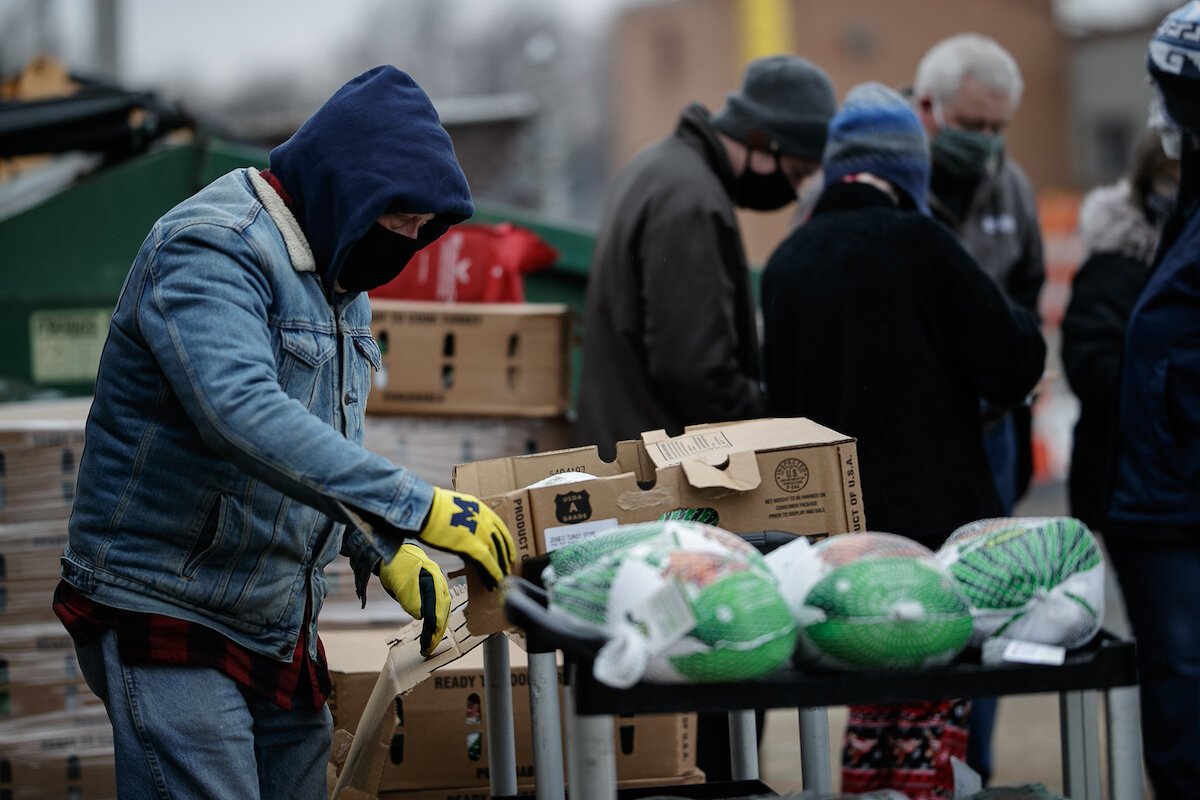A volunteer helps to organize and hand out food boxes and turkeys to families arriving at Holy Redeemer's outreach drive through.
