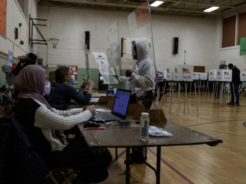 Caitlin Mazurek, 28, poll volunteer and election inspector hands a ballot to a voter at precinct 46 in Pierce Elementary.