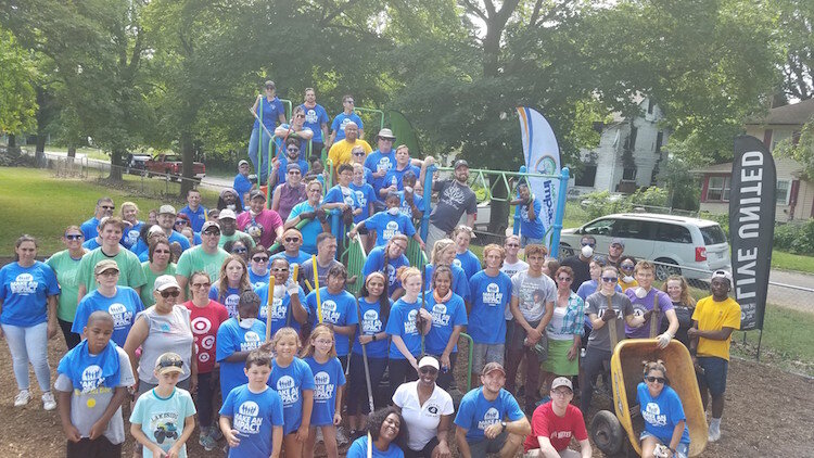 Volunteers gather on the playground equipment at Bassett Park for its grand opening July 27, 2019.