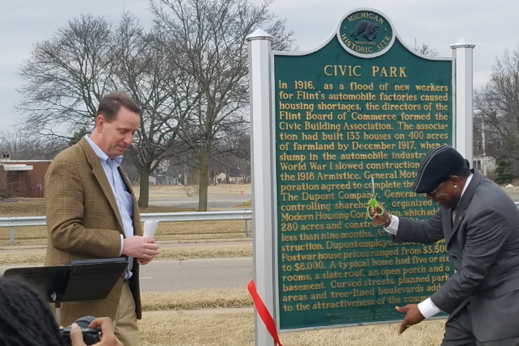 Flint City Councilman Maurice Davis cuts the ribbon at the official rededication ceremony for the Civic Park Neighborhoods historic marker.