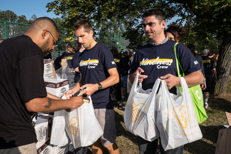 Jon Gries of East Lansing (center) and George Matei of Westland (right) file through the lines of workers bagging groceries at the Convoy of Hope event in Bassett Park in Flint on Saturday.