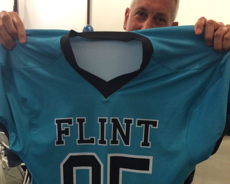 Flint Community Schools athletic director Jamie Foster shows off the look of the new unified Flint sports teams—which will be called the Jaguars.